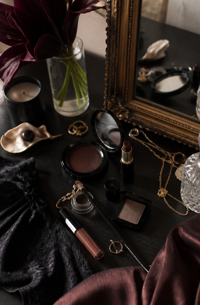 Flat lay of makeup products inspired by dark feminine icons.
