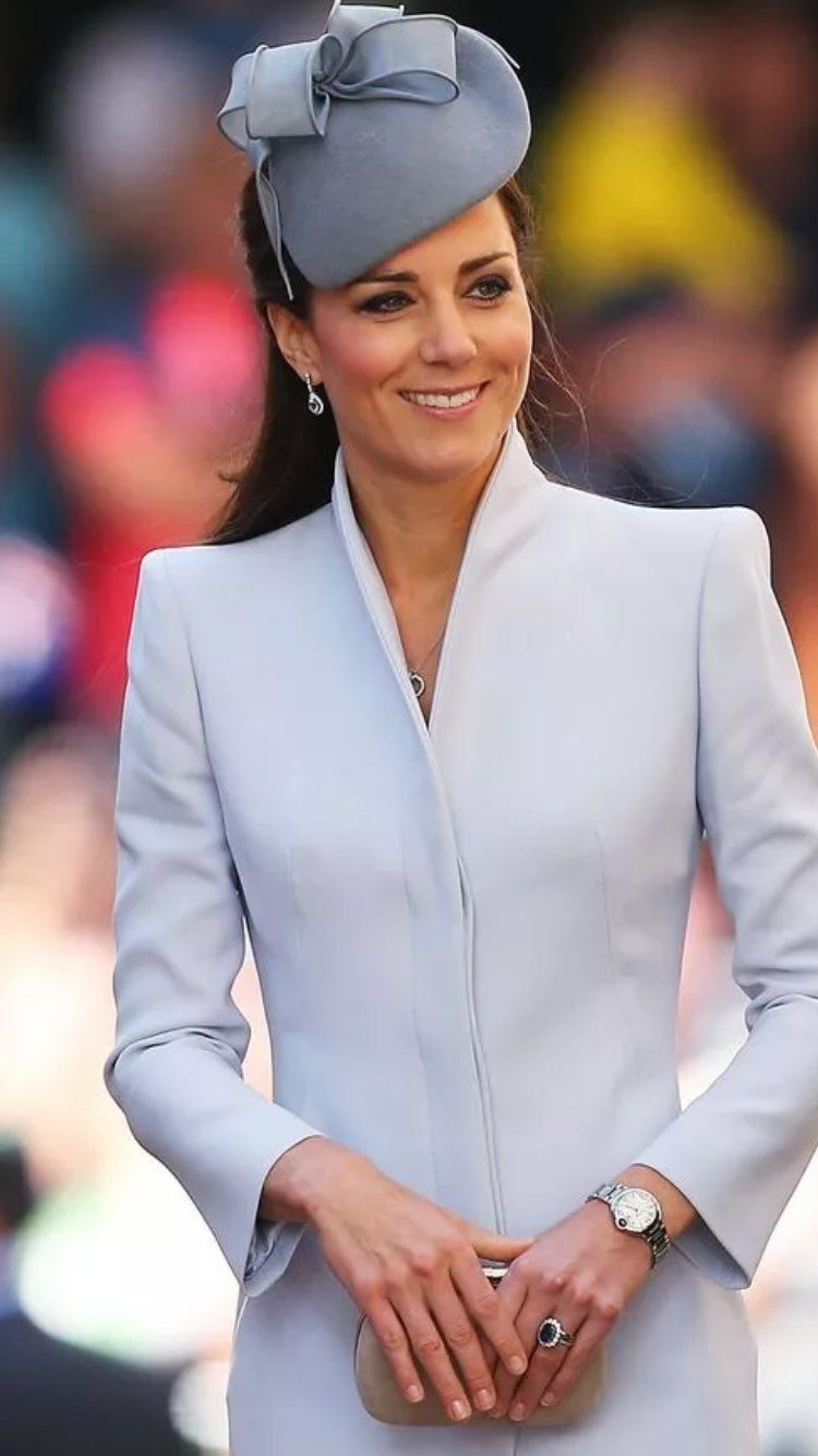 Princess Kate Outfits: 9 Style Templates to Borrow 5 Princess Kate smiling in a light blue outfit, wearing a fascinator, earrings, and holding a clutch.