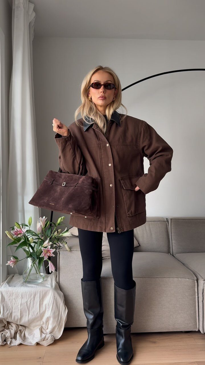 Modest Winter Outfits: 12 Ideas for Cold Days 9 A woman posing in a brown barn jacket, black leggings, and tall black boots.