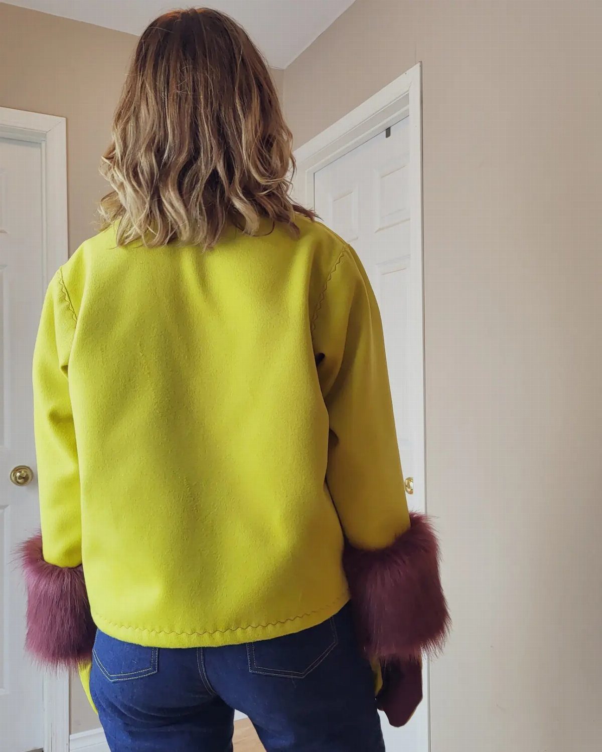 Women's Coat Pattern: 10 Sewing Ideas for Outerwear 8 Woman wearing a bright yellow coat with large reddish-brown fur cuffs from behind.
