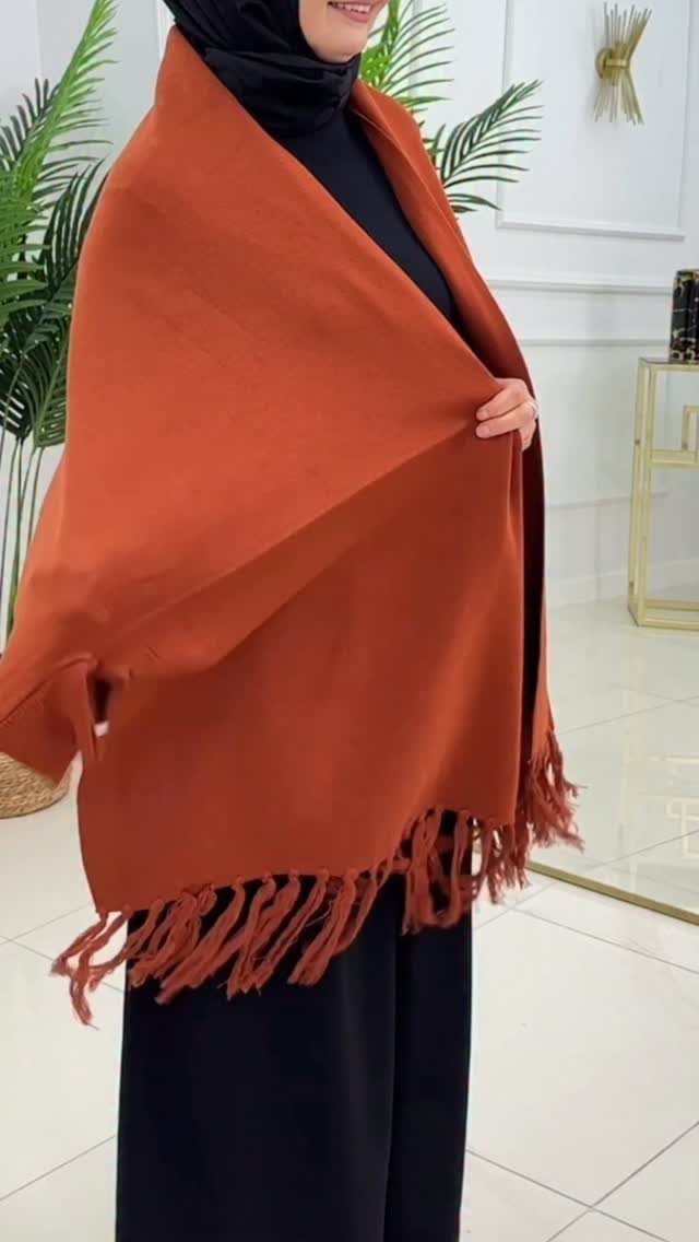 Modest Winter Outfits: 12 Ideas for Cold Days 10 A person wearing a black hijab and a large burnt orange fringed shawl over black clothing.