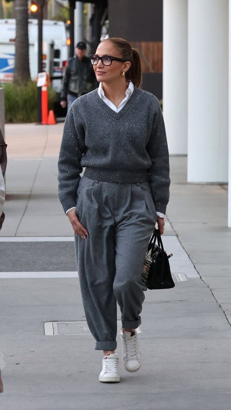 10 Knit Sweater Outfit Ideas for Fall Through Winter 2026 6 Woman walking in a grey knit sweater and matching grey trousers with white sneakers.