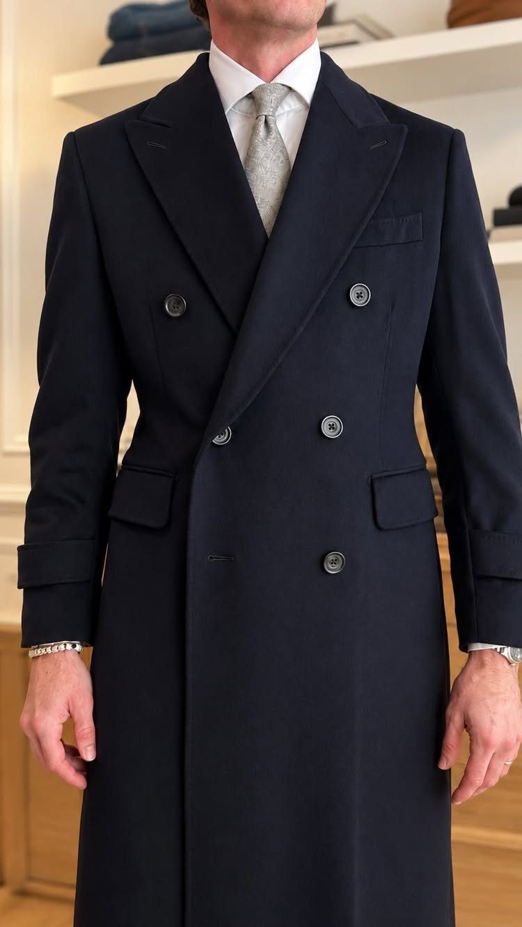 Tailored Wool Coat Styles: 8 Women's Ideas for 2026 5 A man wearing a long, navy blue double-breasted tailored wool coat and a grey tie.