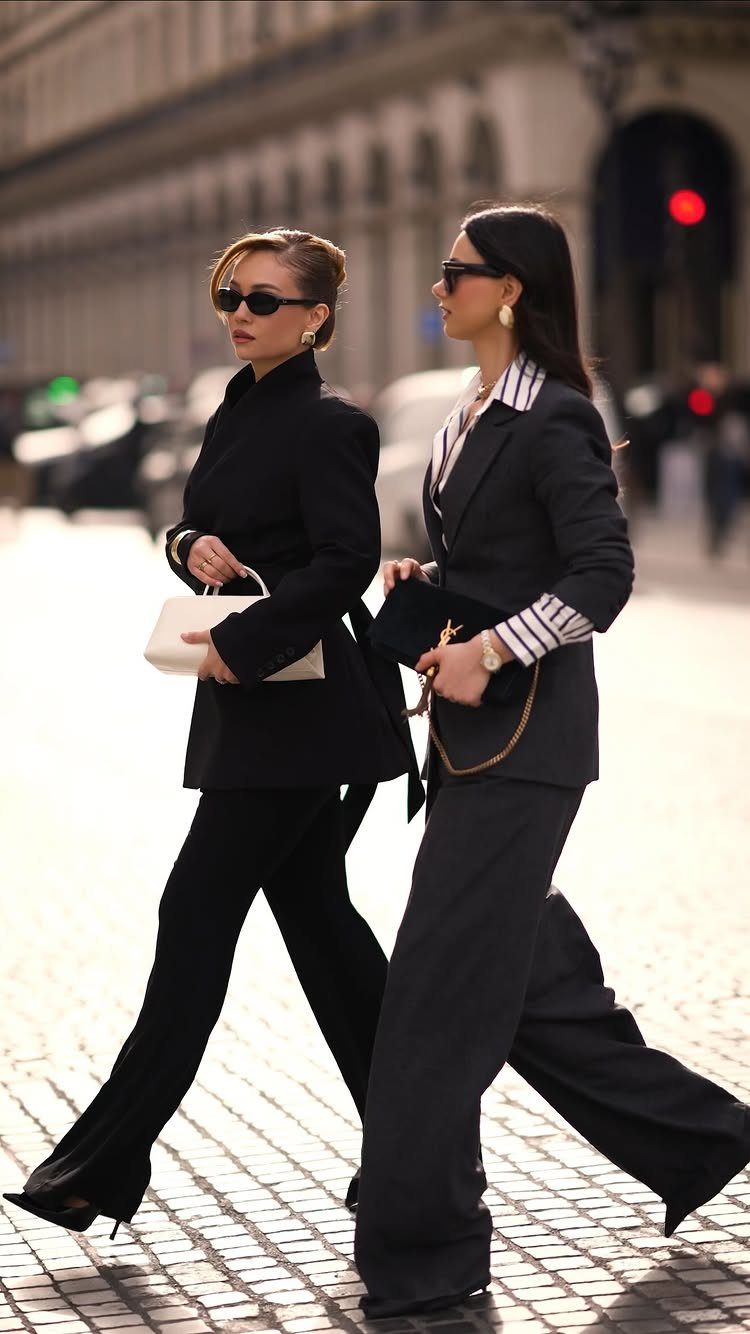 Boss Lady Outfit Ideas: 17 Looks for 2026 9 Two women in sophisticated black business attire walking confidently along a cobblestone city street.