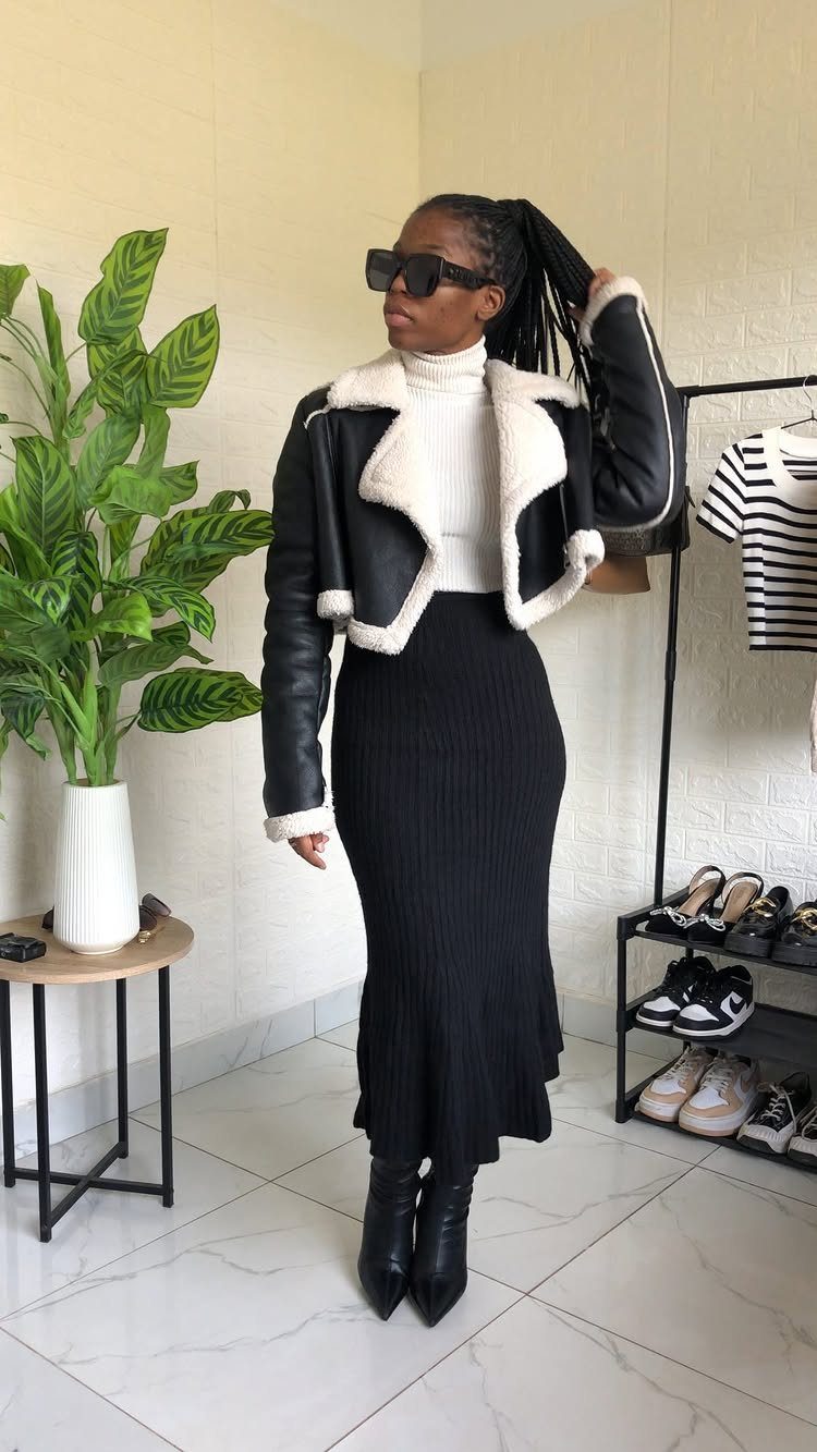 Modest Winter Outfits: 12 Ideas for Cold Days 13 A woman posing in a black shearling jacket, white turtleneck, and long black skirt.