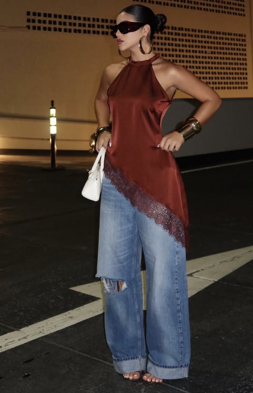 10 Baddie Outfits Casual Enough for Everyday, Styled to Stand Out 8 Woman in a red satin halter top and wide-leg denim jeans posing outdoors at night.