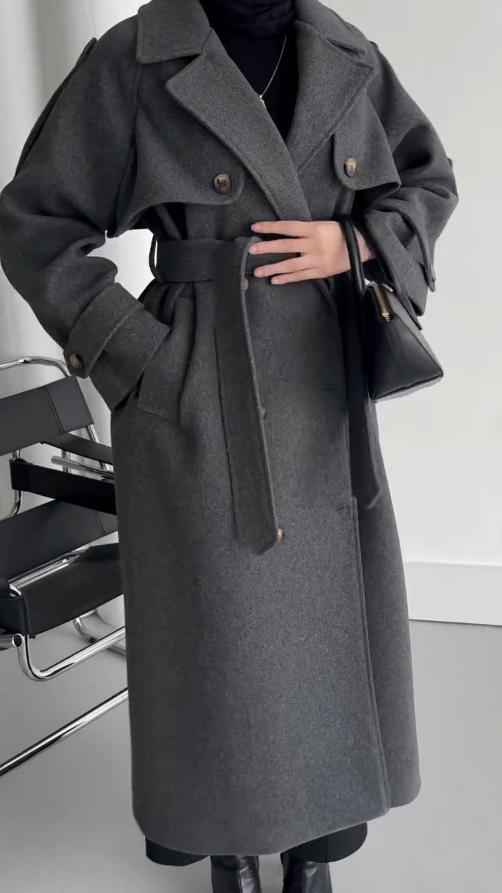 Modest Winter Outfits: 12 Ideas for Cold Days 8 A person wearing a long, belted grey structured wool coat and a black hijab.