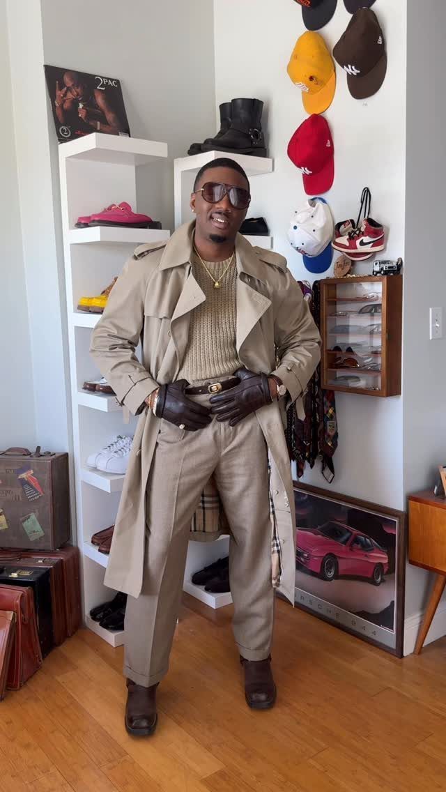 15 Trench Coat Outfit Ideas for Dressing With Intention 6 Man in a tan trench coat, beige turtleneck, trousers, and dark brown boots standing indoors.